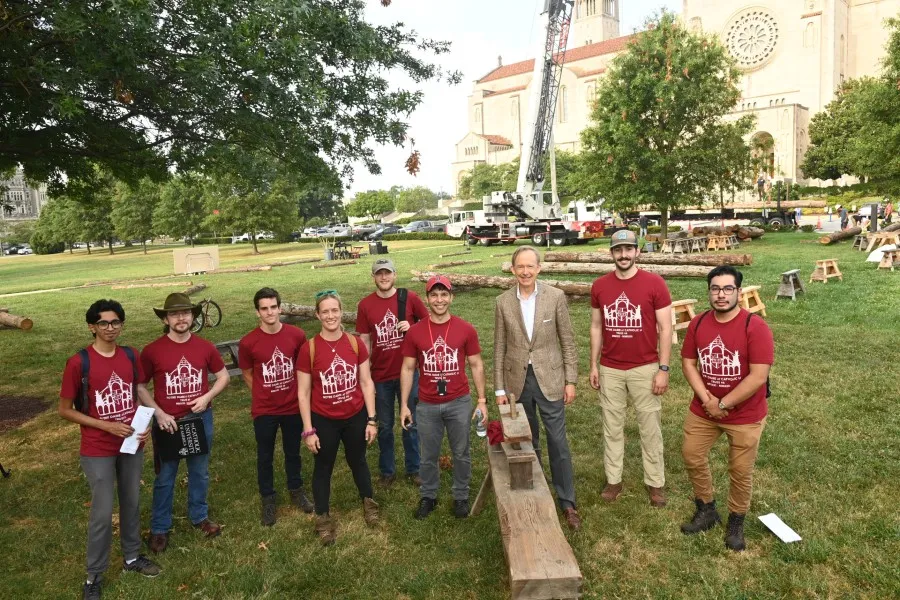 Professors and students stand in front of the Basilica of the National Shrine of the Immaculate Conception at The Catholic University of America's campus, to begin building truss number six of Notre Dame Cathedral in France.?w=200&h=150